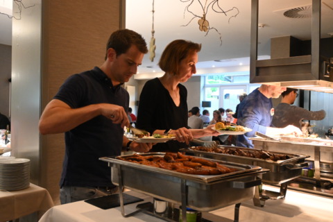 Groep collega's die zich samen bedienen aan het uitgebreid buffet in het restaurant op het einde van een seminarie dag bij Nestia Hospitality Group