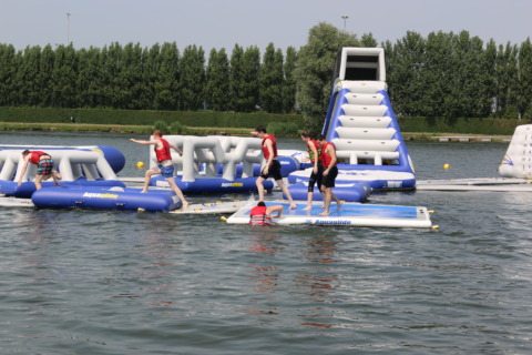 Teambuilding activiteit op opblaasbaar waterpark bij ibis budget Brugge Jabbeke Deelnemers op een opblaasbaar waterparcours tijdens een teambuilding activiteit bij ibis budget Brugge Jabbek